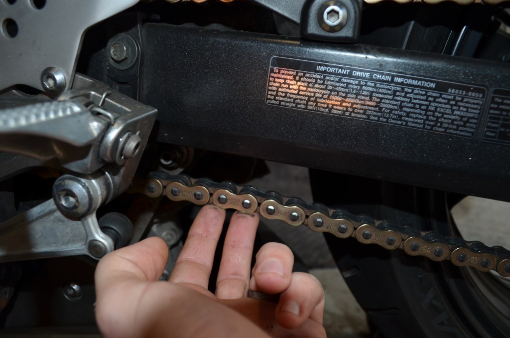 While the bike is on its stand, check the slack by simply pressing the chain up towards the swingarm with your fingers. Your bike will recommend what distance it is supp